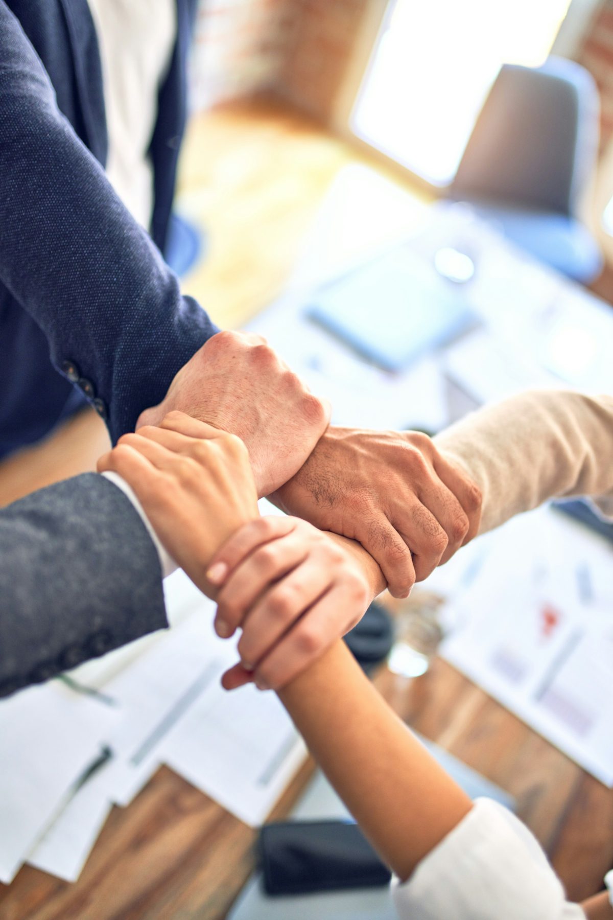 Colleagues placing their hands together over a desk
