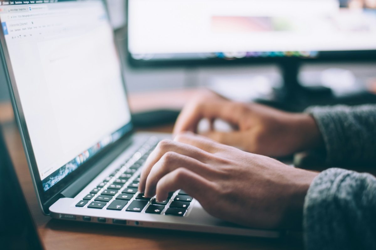 Hands typing on a laptop at home